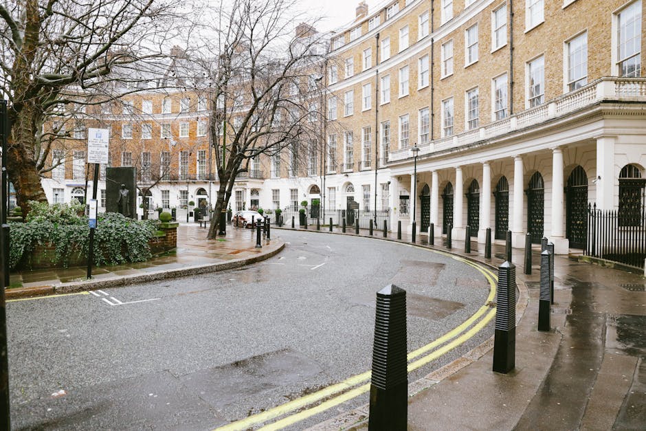 A multi-storey residential building made of red brick with ornate architectural details, including bay windows and decorative stonework, situated on a city street. The ground-floor entrance has a smal